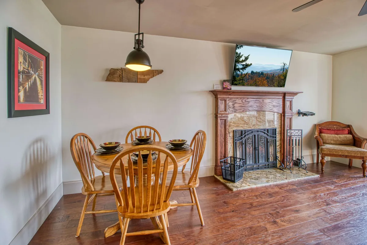 An inviting dining area with a central table, plush armchair, fireplace, and TV. The space is arranged for shared meals and relaxed moments, with warm lighting that encourages connection and togetherness.