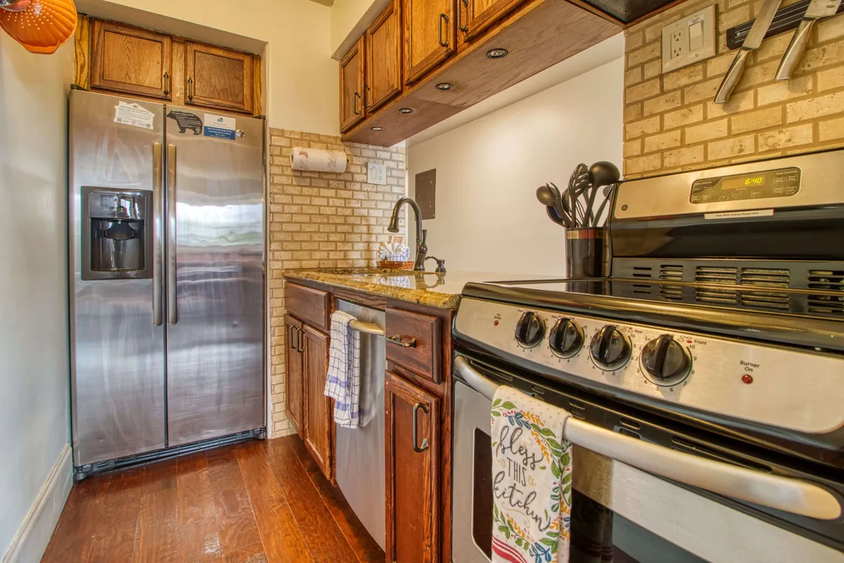 A cozy yet functional kitchen featuring stainless steel appliances—including a refrigerator and oven—along with granite countertops and wood cabinetry. The space is well-lit and equipped for both everyday meals and special gatherings.